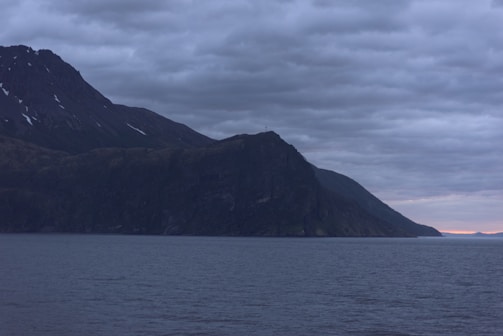 A dark-themed still from a cinematic video featuring a serene North Sulawesi coastline at dusk