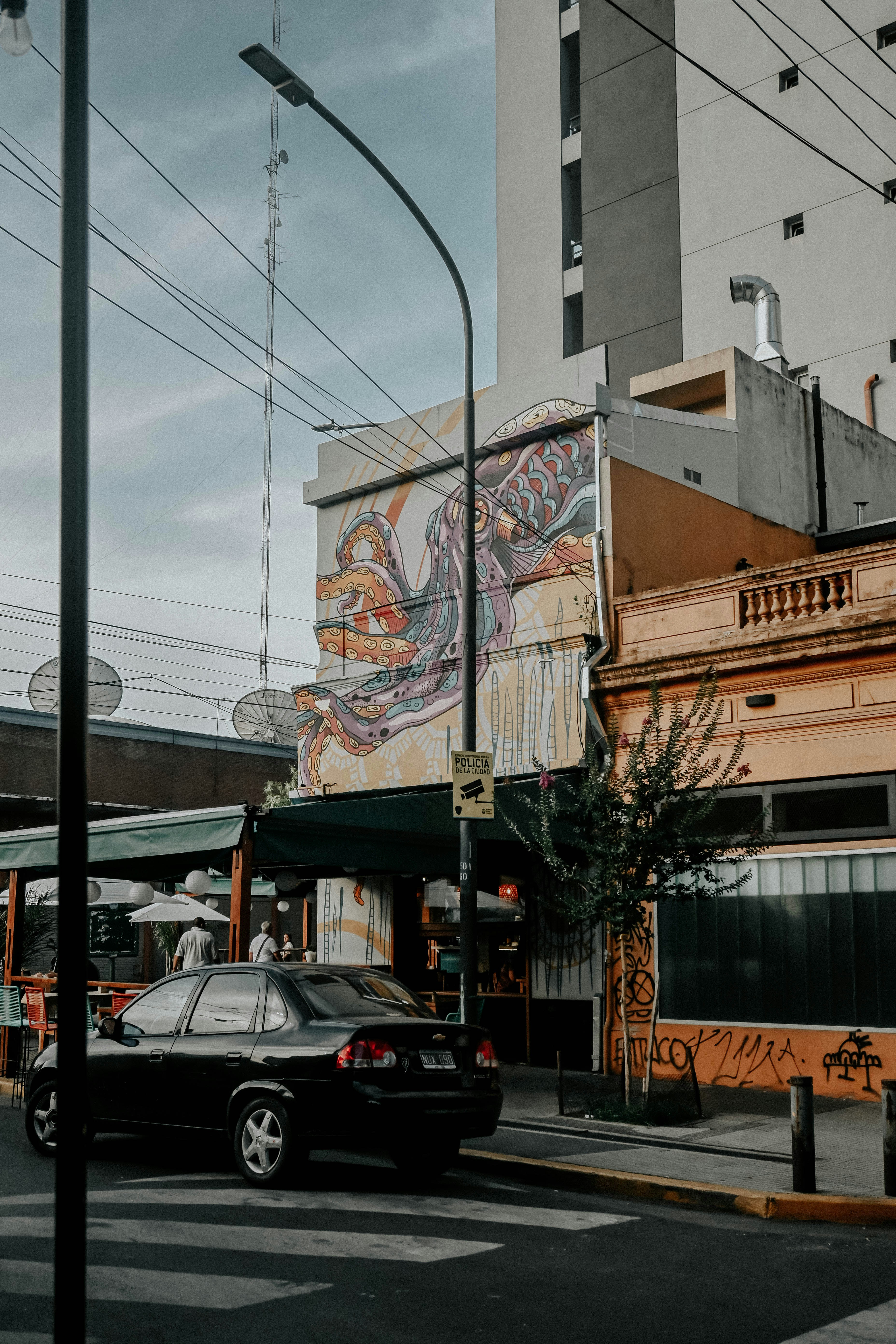 a black car driving down a street next to tall buildings