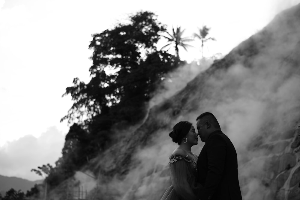 a man and a woman standing in front of a mountain