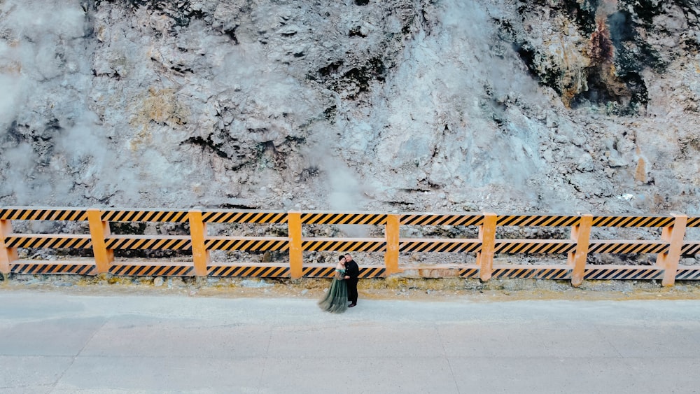 a person walking down a road next to a mountain