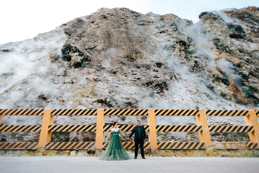 a man and woman standing next to each other in front of a mountain