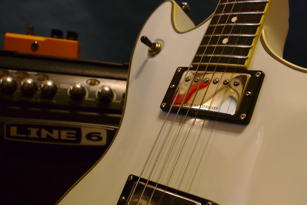 a white electric guitar sitting next to a amp