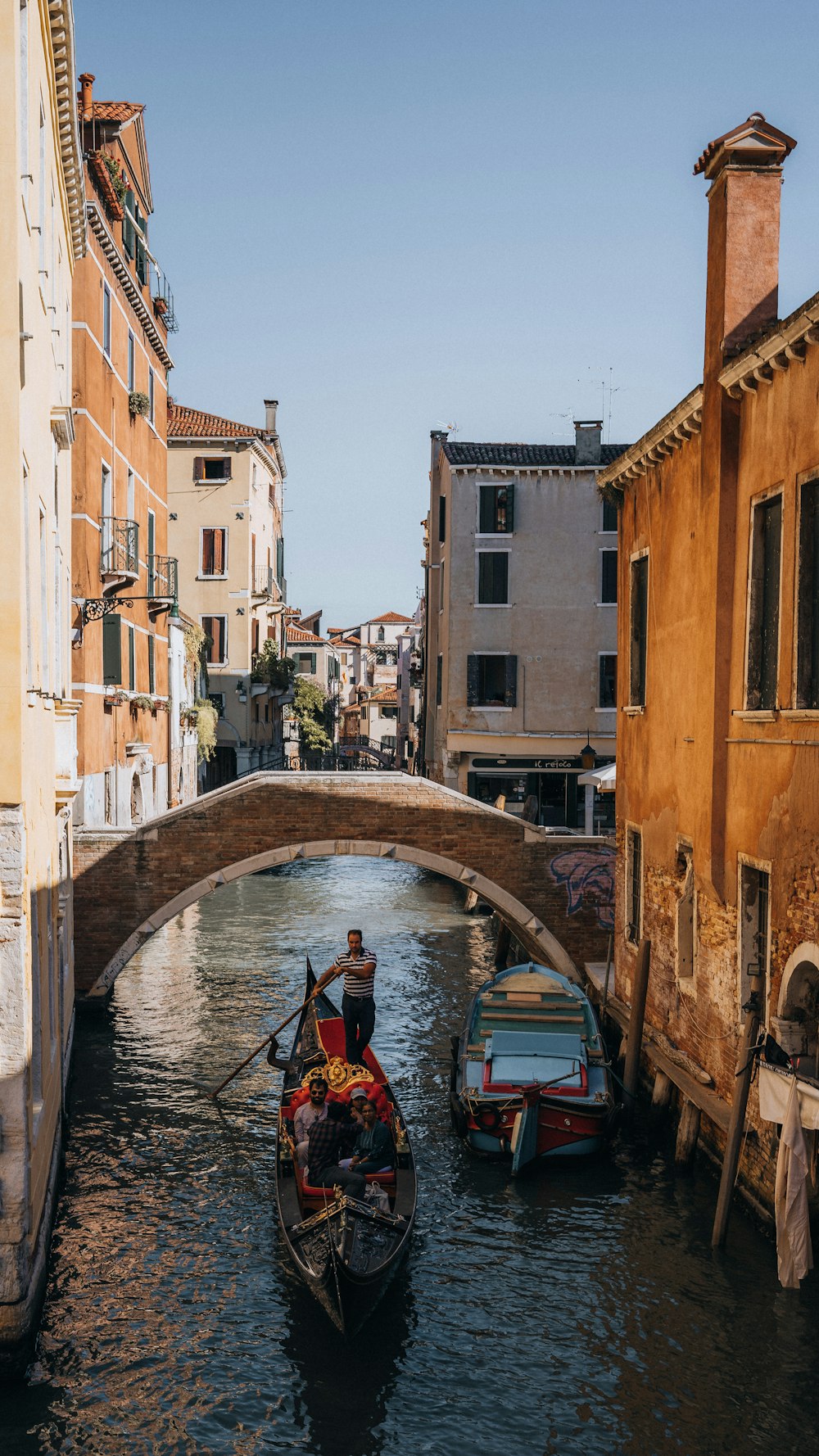 a man riding a boat down a river under a bridge