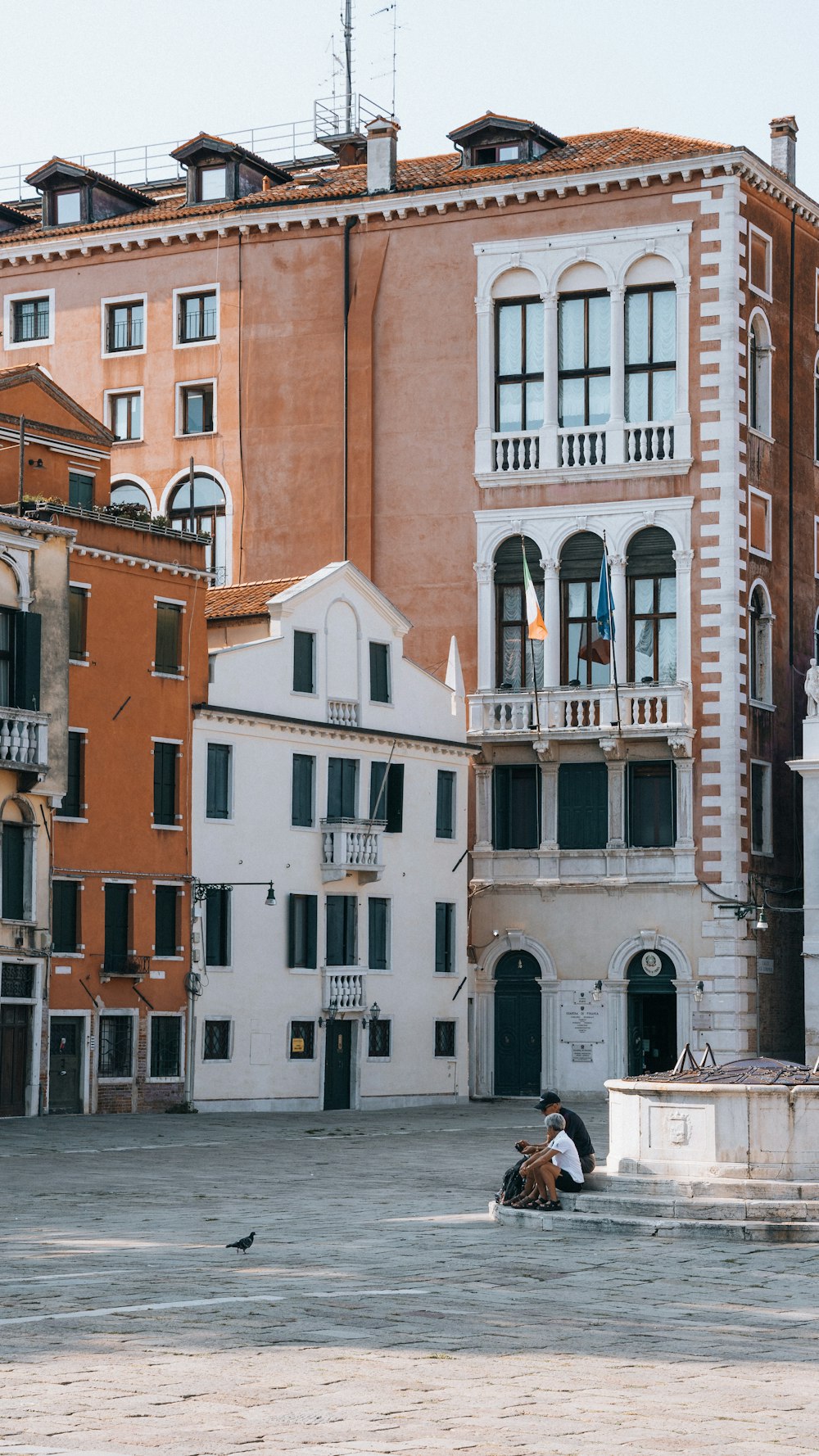 a couple of people sitting on a bench in front of a building