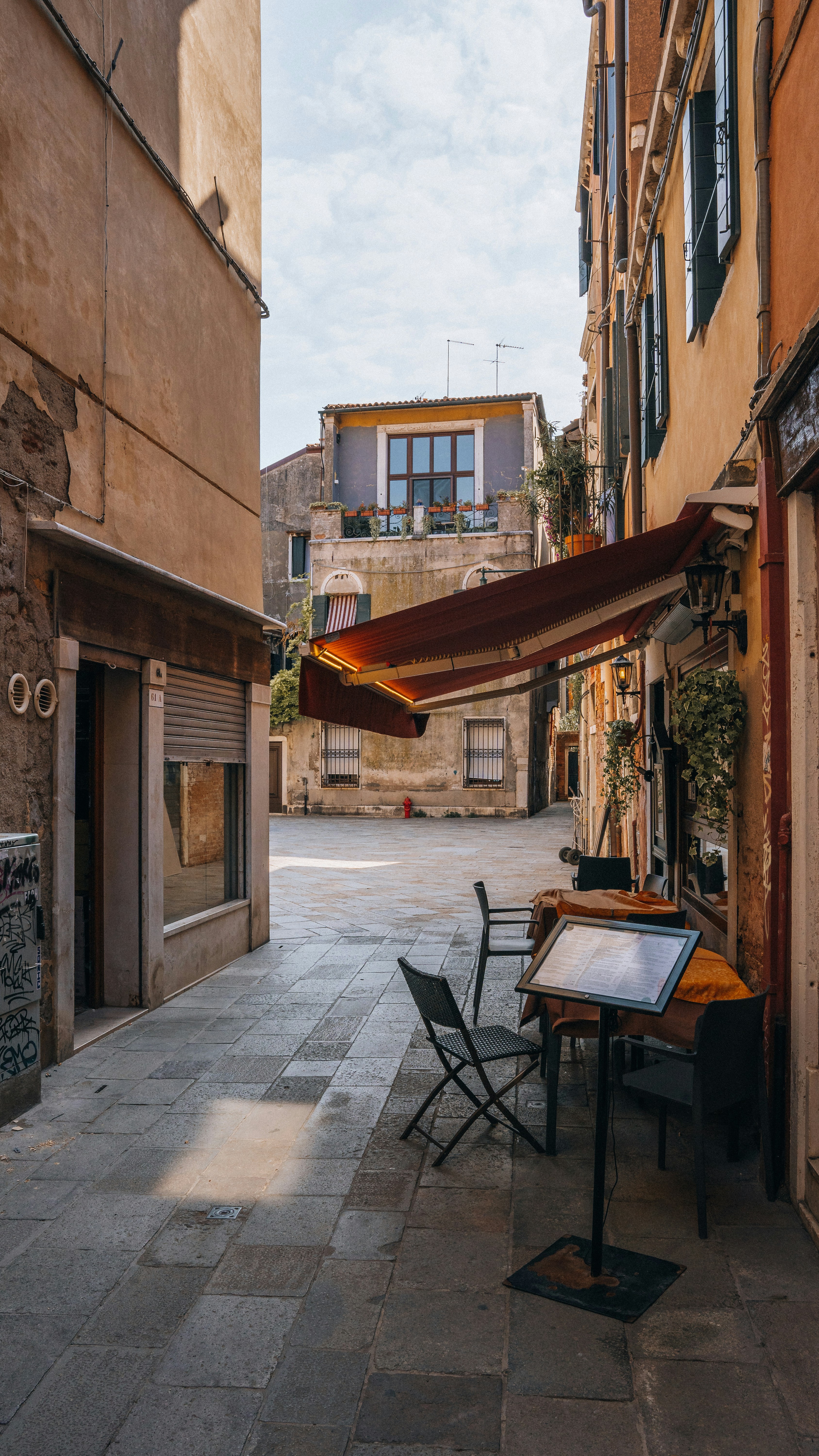 a table and chairs on a sidewalk next to a building