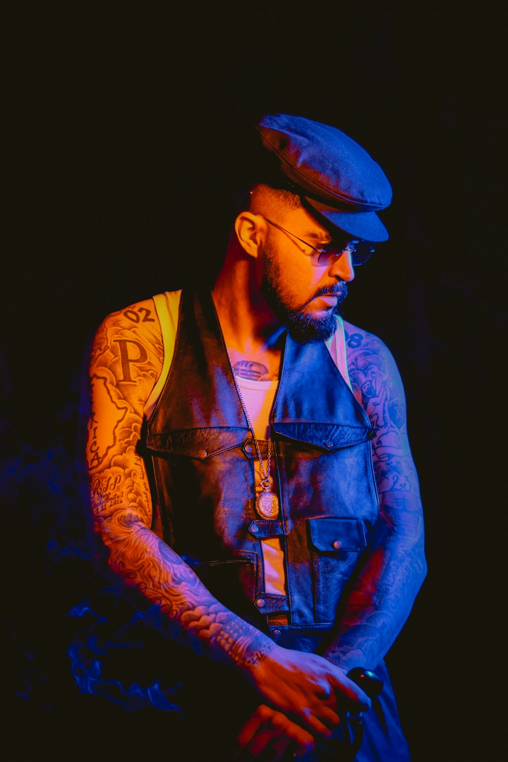 a man with tattoos and a blue vest