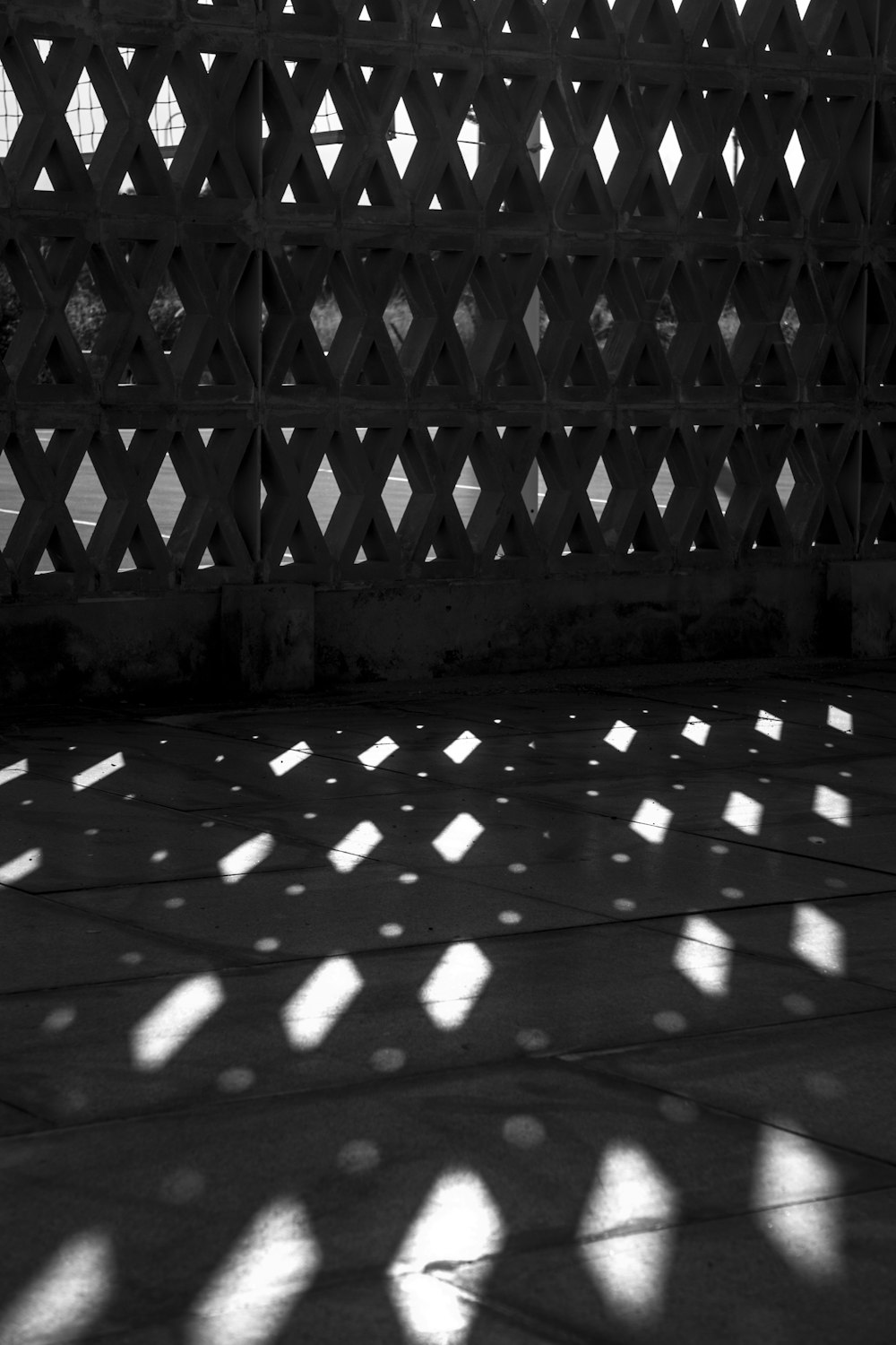 a black and white photo of the shadow of a fence