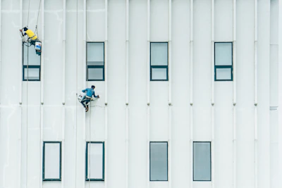 Close-up of a worker painting a building exterior at height with safety gear.