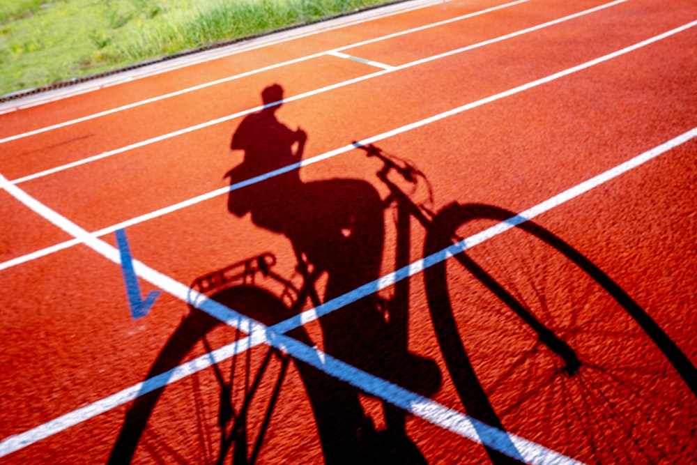 a shadow of a person riding a bike on a track