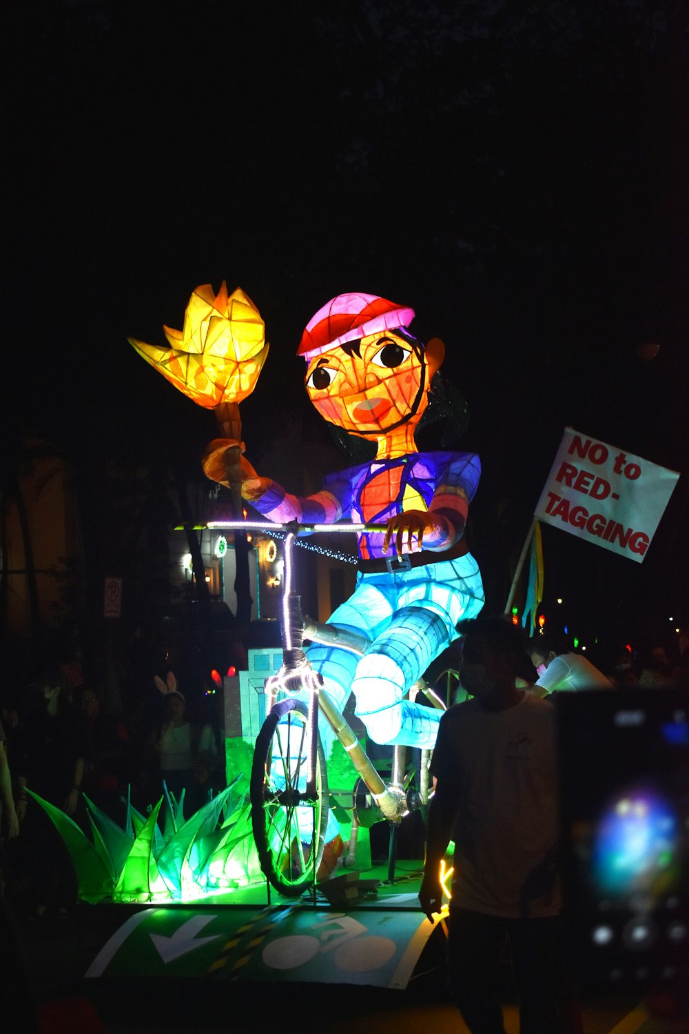 a person riding a bike with a lantern in the shape of a fish on it