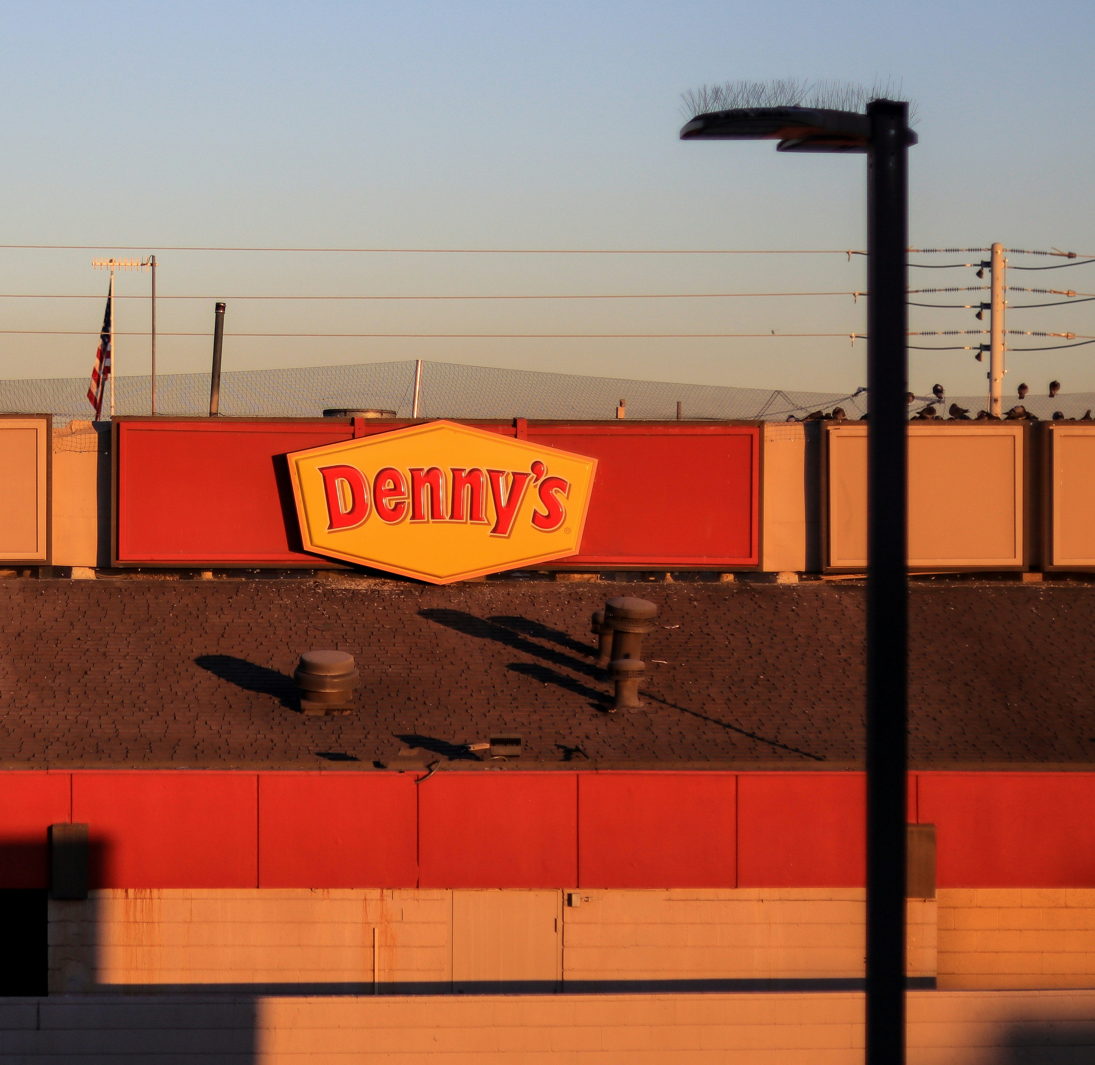 A sign for a restaurant called denny's on the side of a building photo