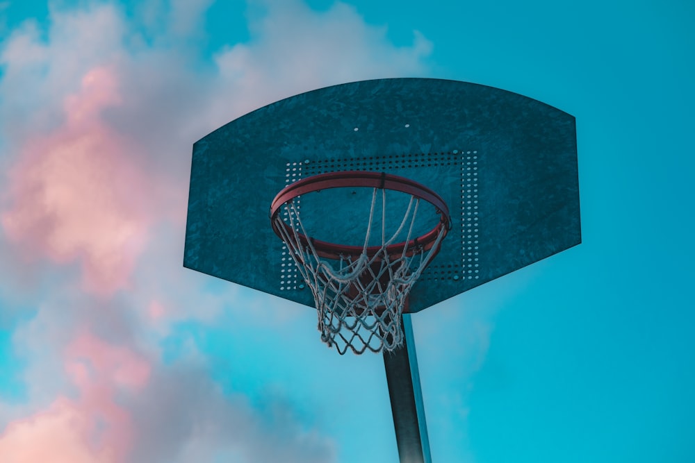 a basketball hoop with a blue sky and clouds in the background