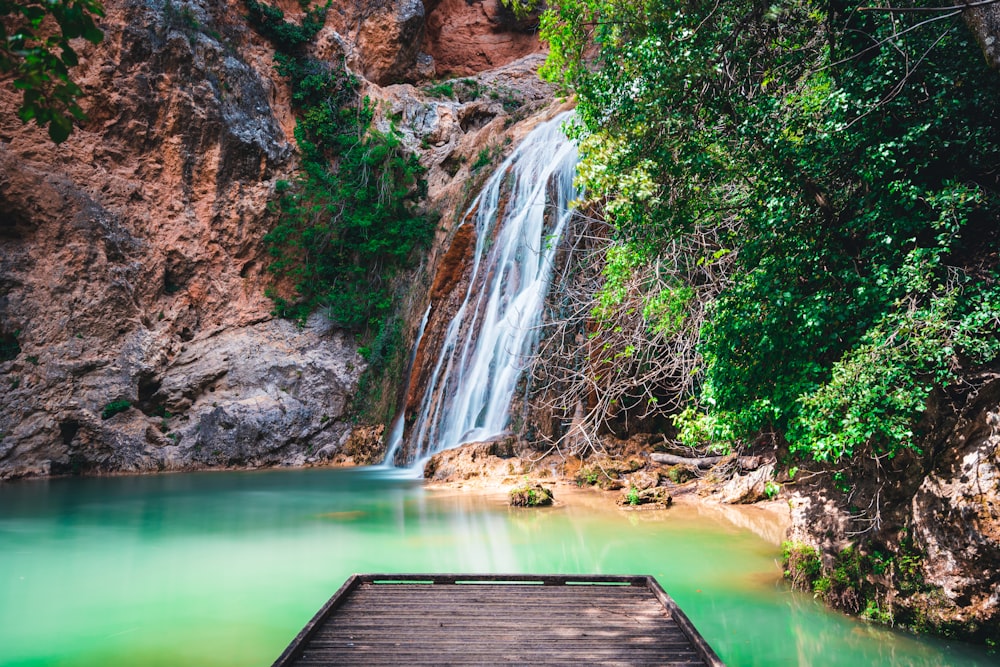 a wooden dock sitting in front of a waterfall