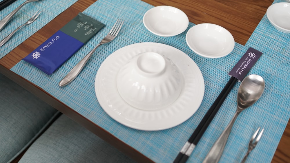 a table with a blue place mat and silverware