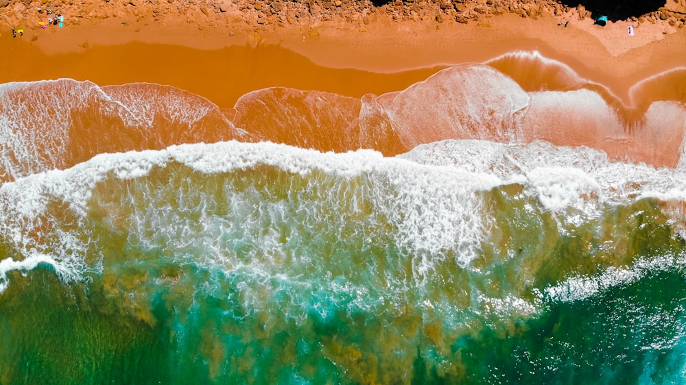 Una vista aérea de una playa con olas y arena naranja