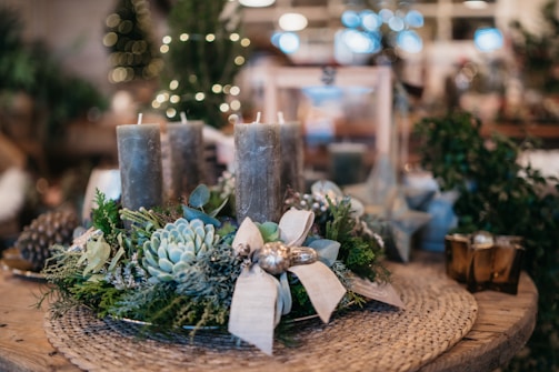 Close-up of a rustic wooden table centerpiece with candles and greenery.