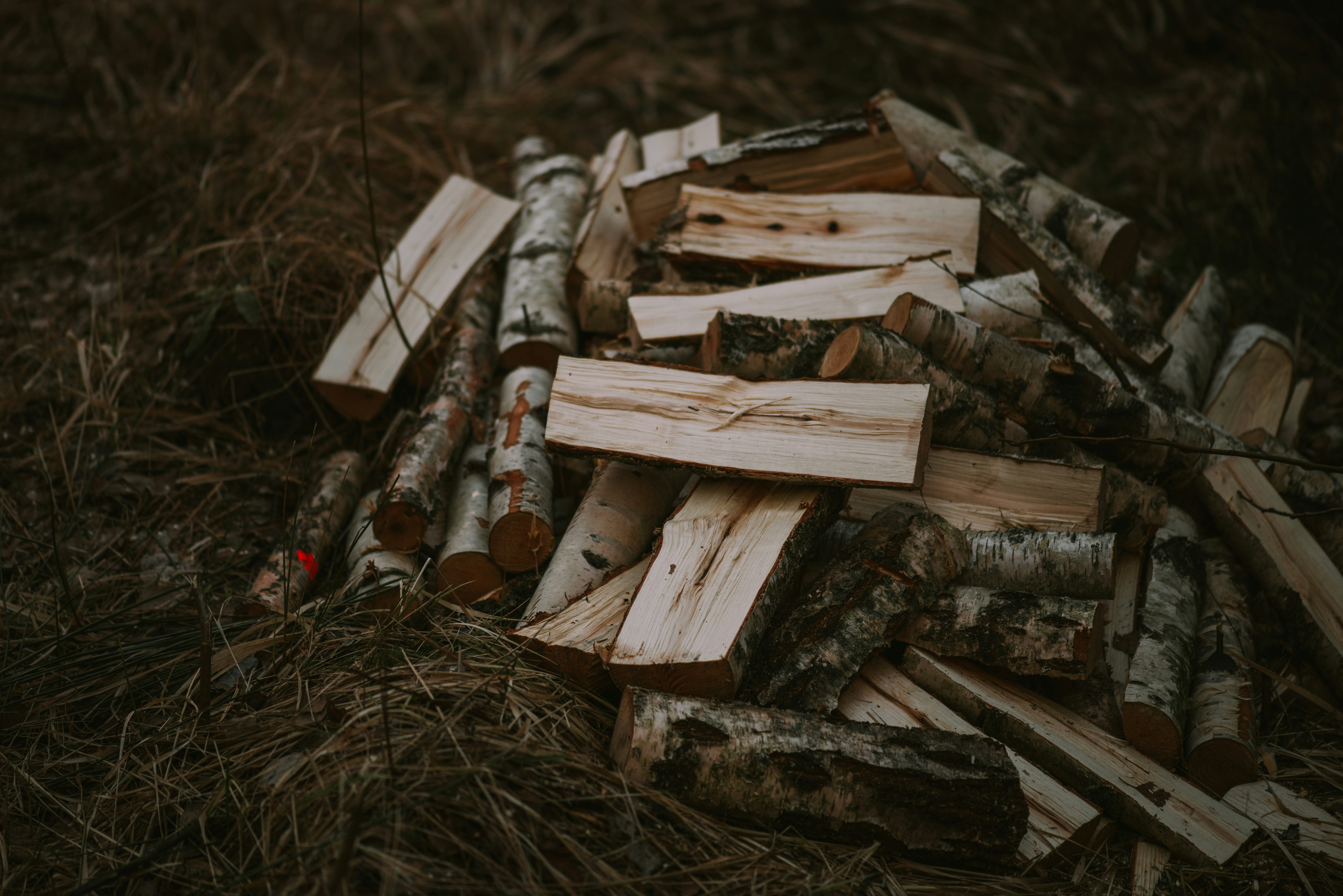 a pile of wood sitting on top of a grass covered field