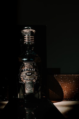 Elegant dark bottle of Sacáis licor de hinojo with a subtle golden glow on a black velvet background