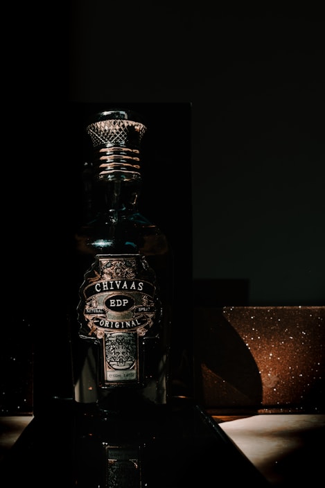 Elegant dark bottle of Sacáis licor de hinojo with a subtle golden glow on a black velvet background