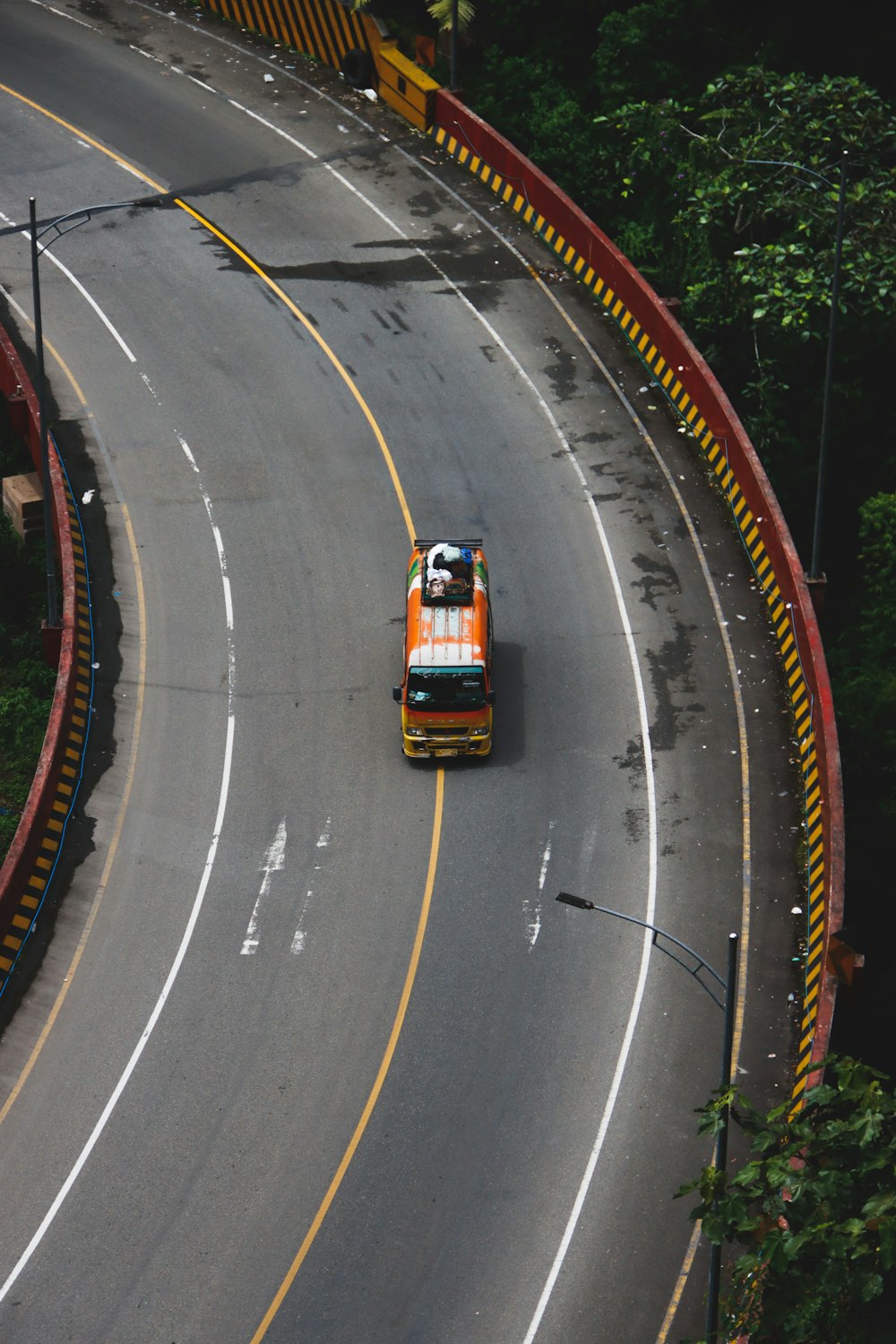 an orange and white bus driving down a curvy road