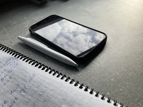 An open notebook with handwritten notes and a smartphone displaying a buying guide article