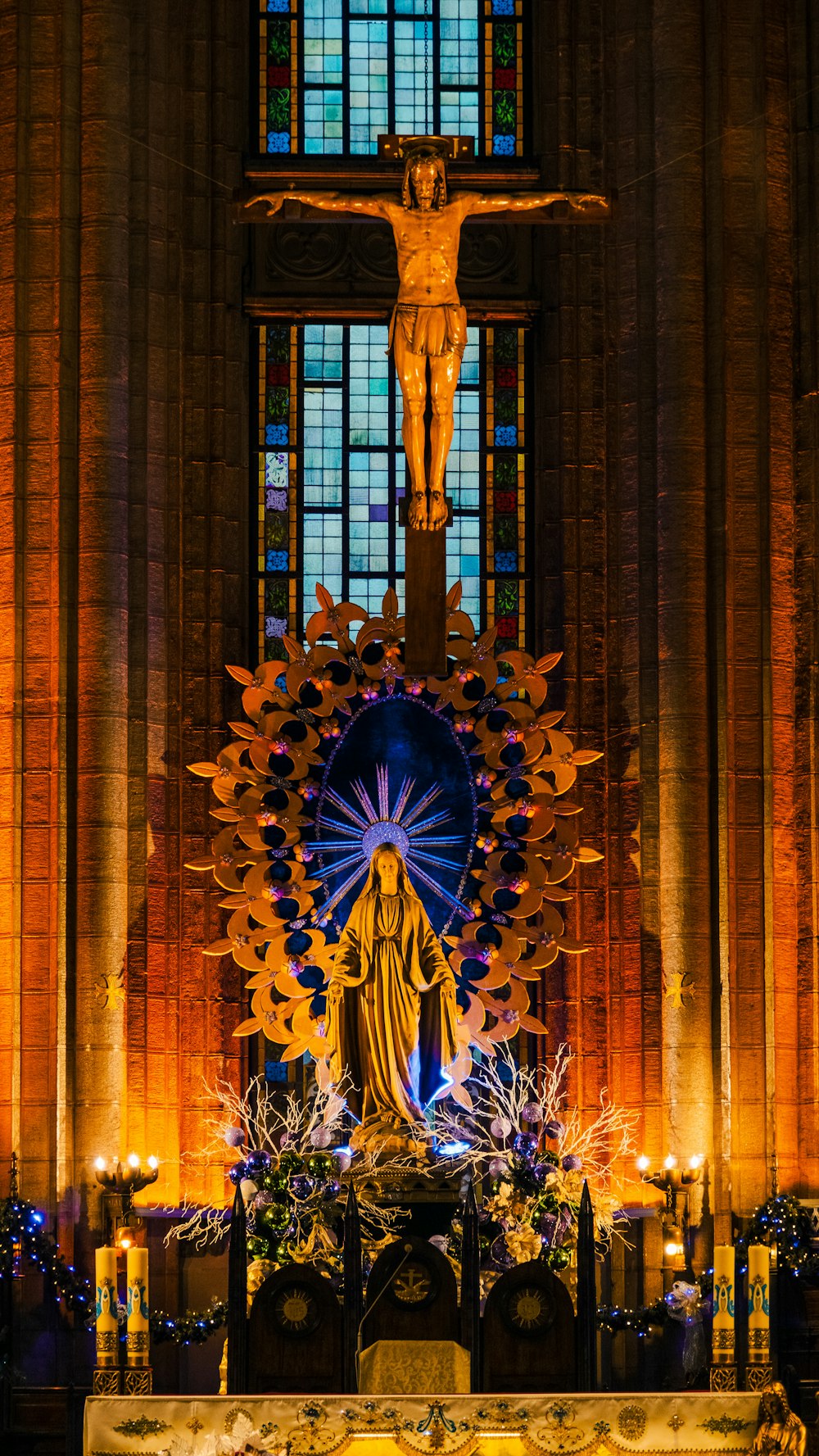 a statue of jesus in front of a stained glass window