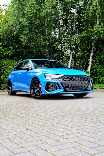 a blue car parked in front of some trees
