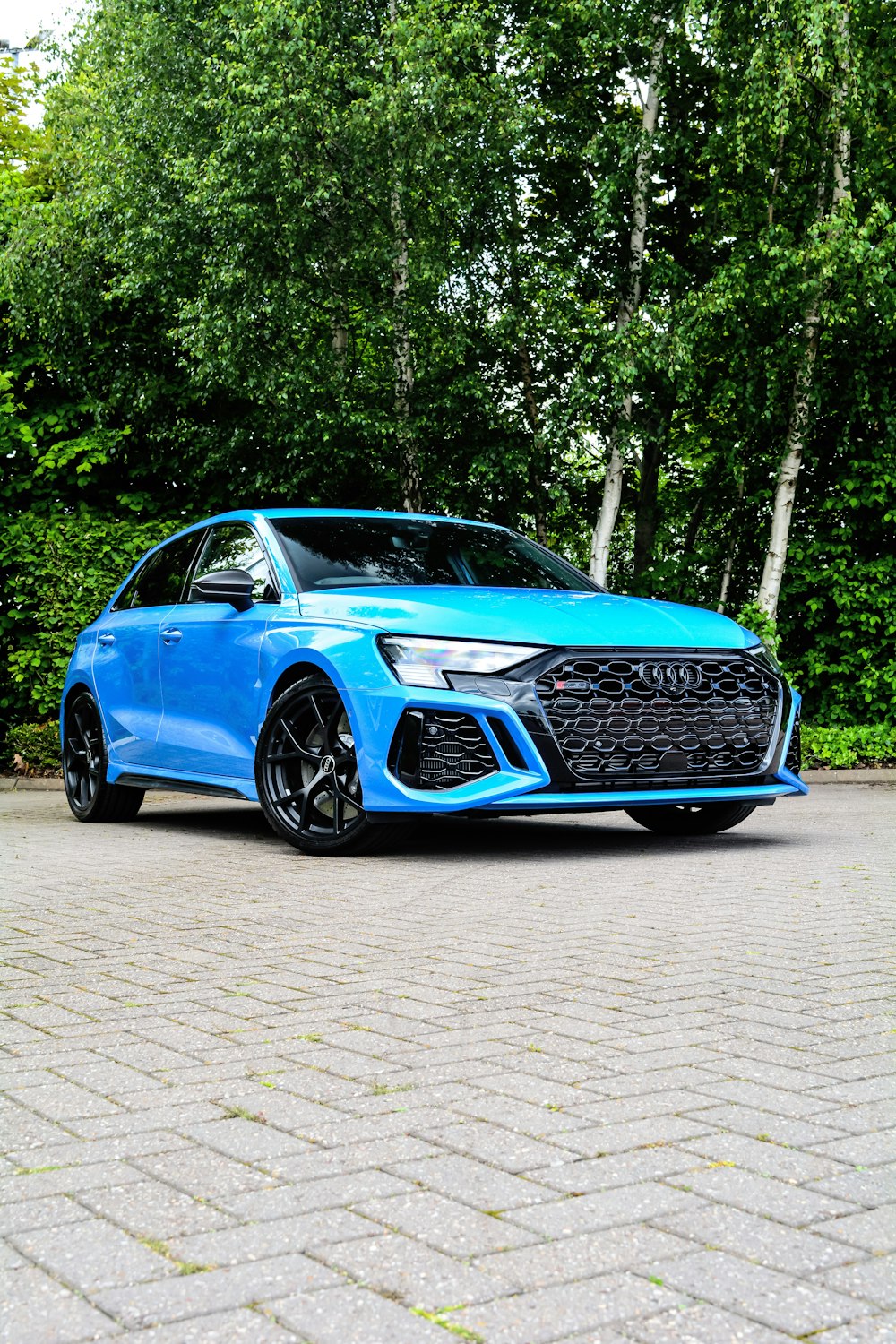 a blue car parked in front of some trees