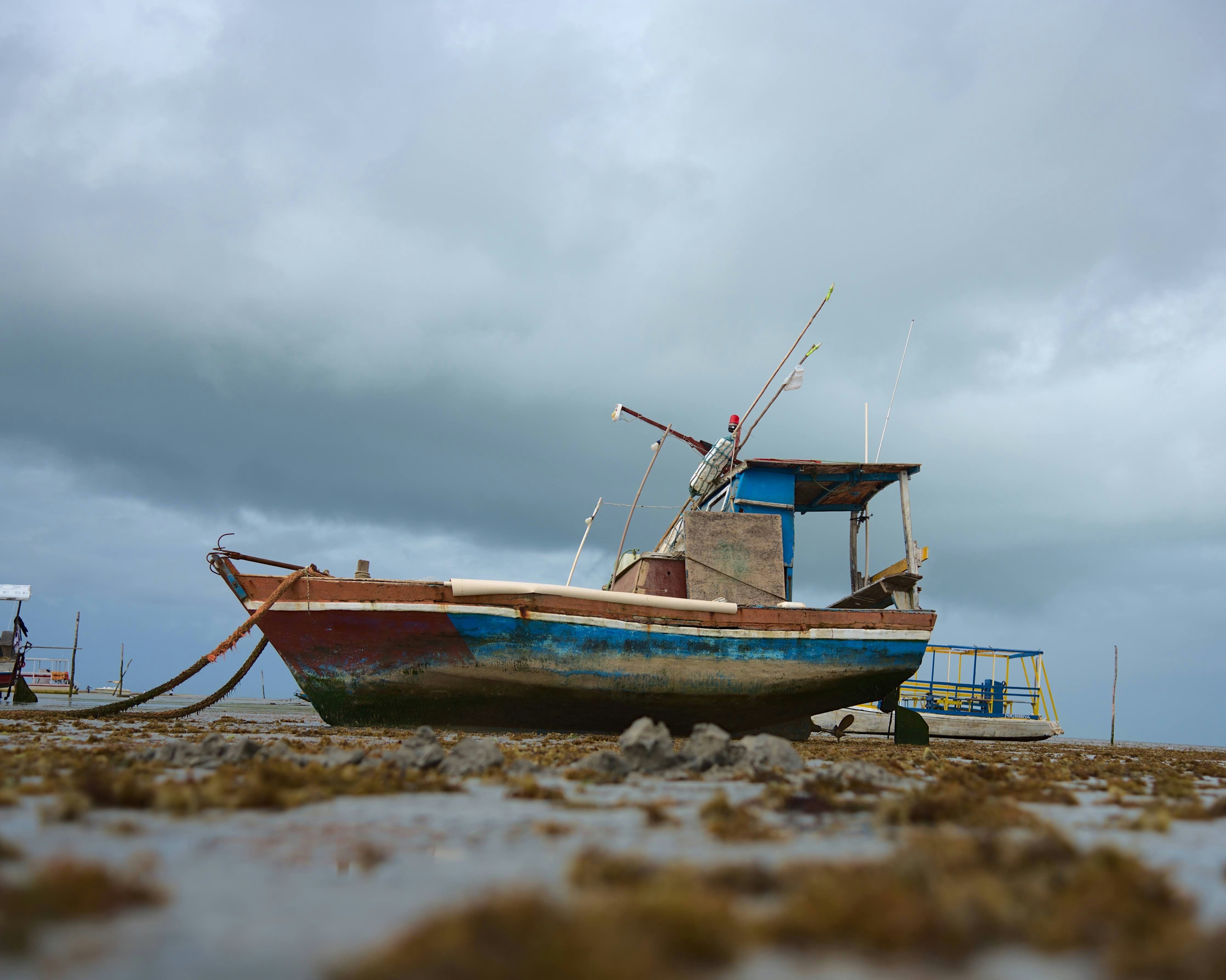 a boat sitting on top of a sandy beach, 