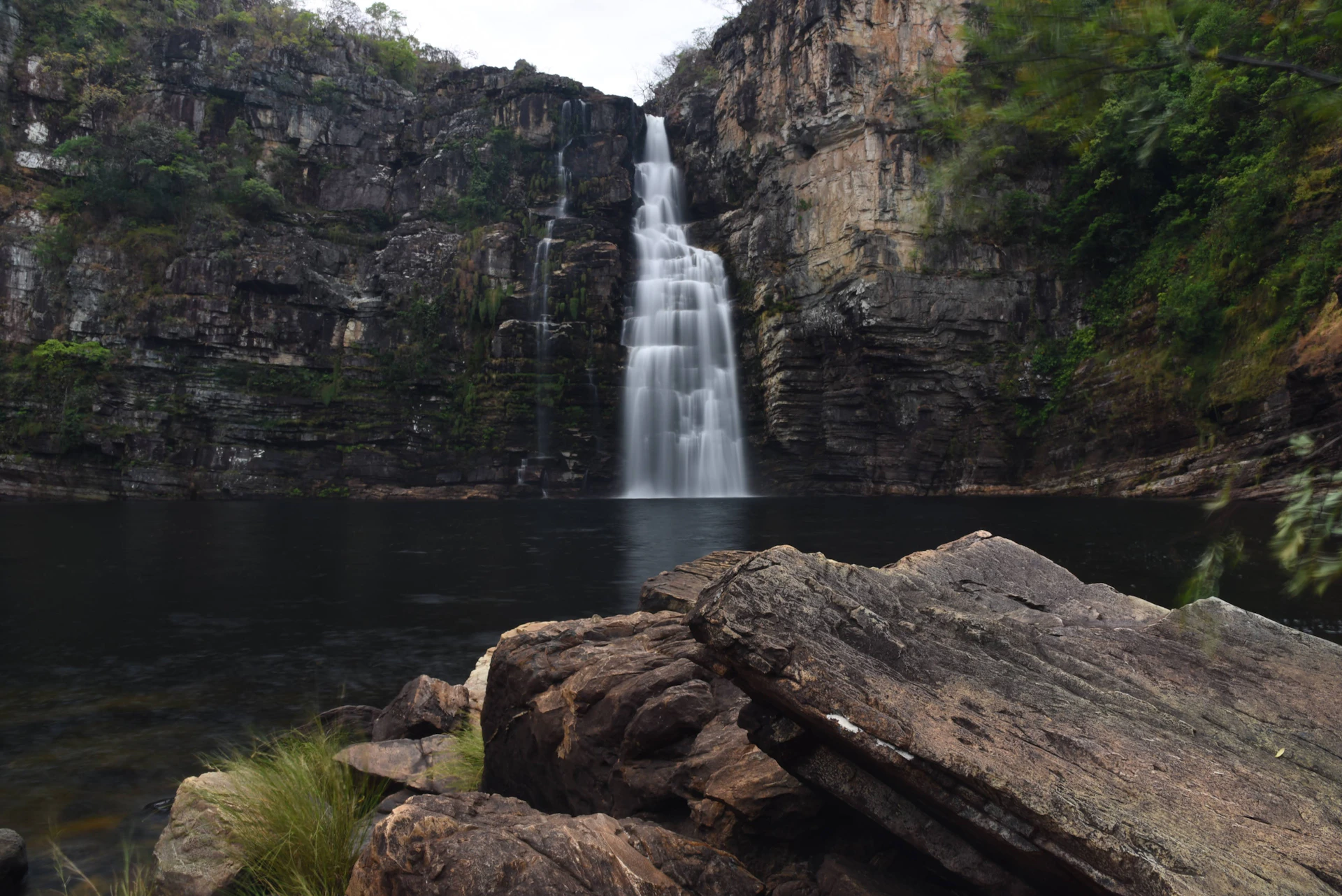 a waterfall with a large rock in front of it