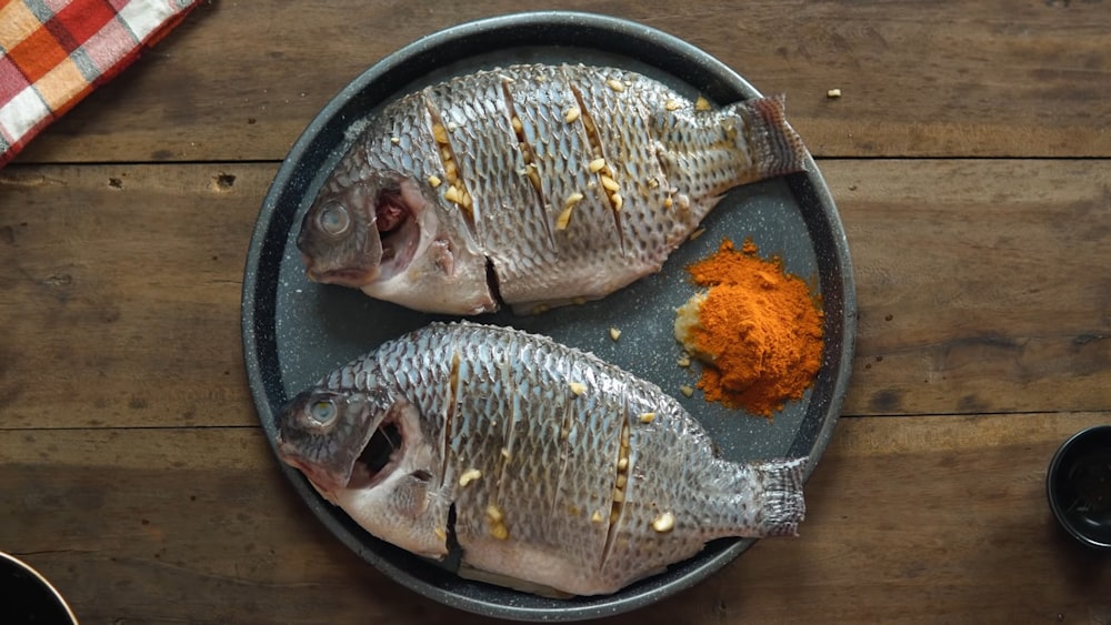 two fish are on a plate with spices