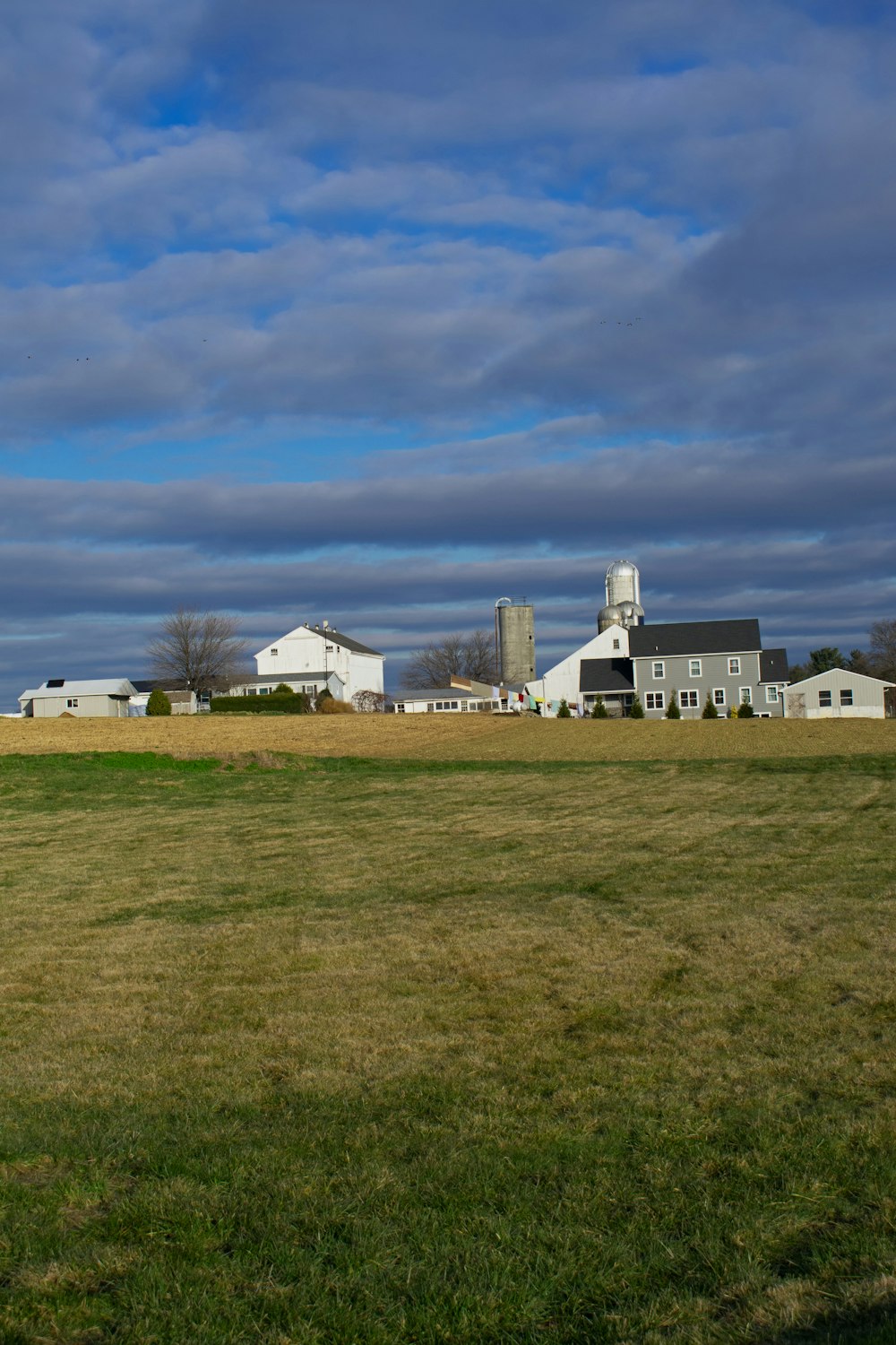 a field with a barn and silos in the background
