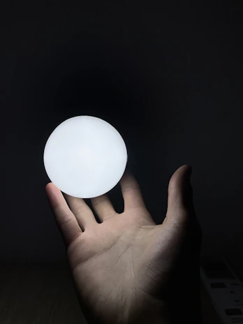 A serene spiritual guide gently holding a glowing orb of light in a calm, softly lit room.