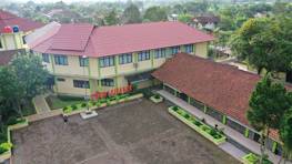 An aerial view of a modern Italian school building surrounded by greenery.