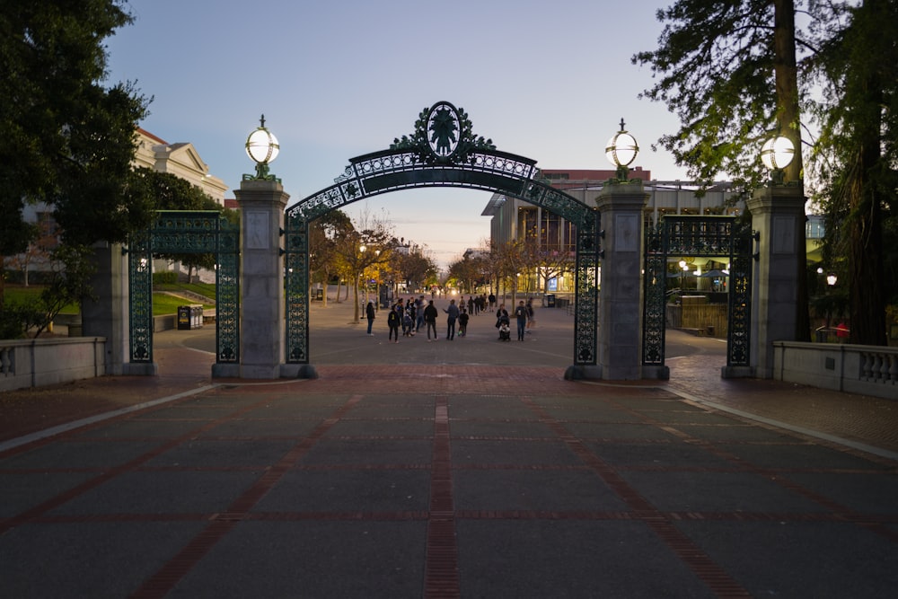 a group of people walking down a street under an arch