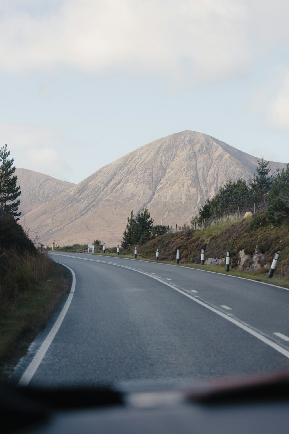 a car driving down a road with a mountain in the background