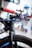 Close-up view of a bicycle featuring a blue handlebar with red grips. The tire is a rugged, all-terrain type and prominently displays the 'RaceKing' branding. A black mount or accessory is attached to the handlebar, and the background is blurred, suggesting a workshop environment.
