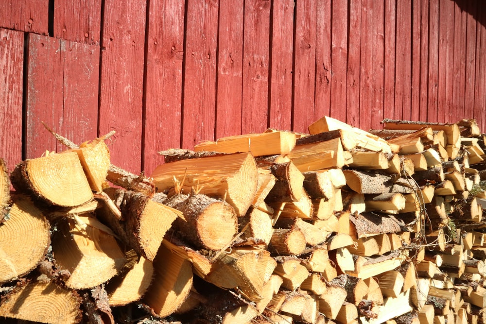 a pile of wood sitting next to a red barn