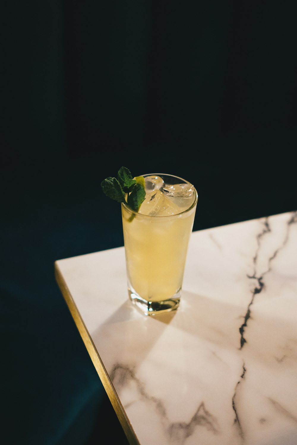 a glass of lemonade sitting on top of a marble table