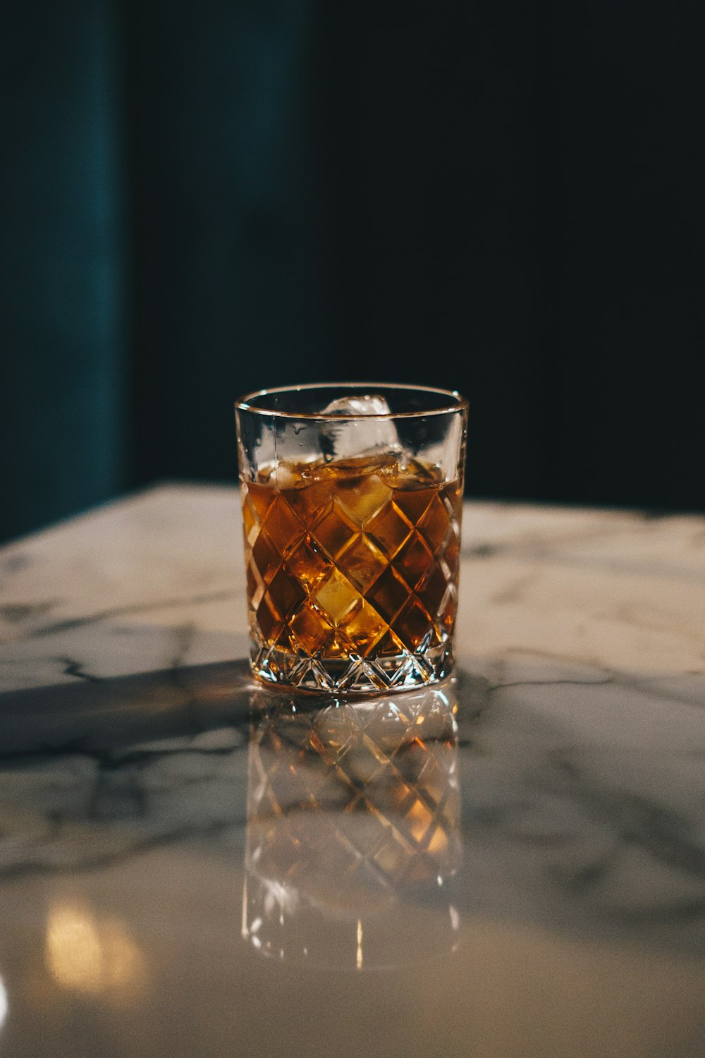 Un vaso de whisky sentado encima de una mesa
