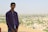 Young man reviewing land documents with a scenic view of open fields behind him.