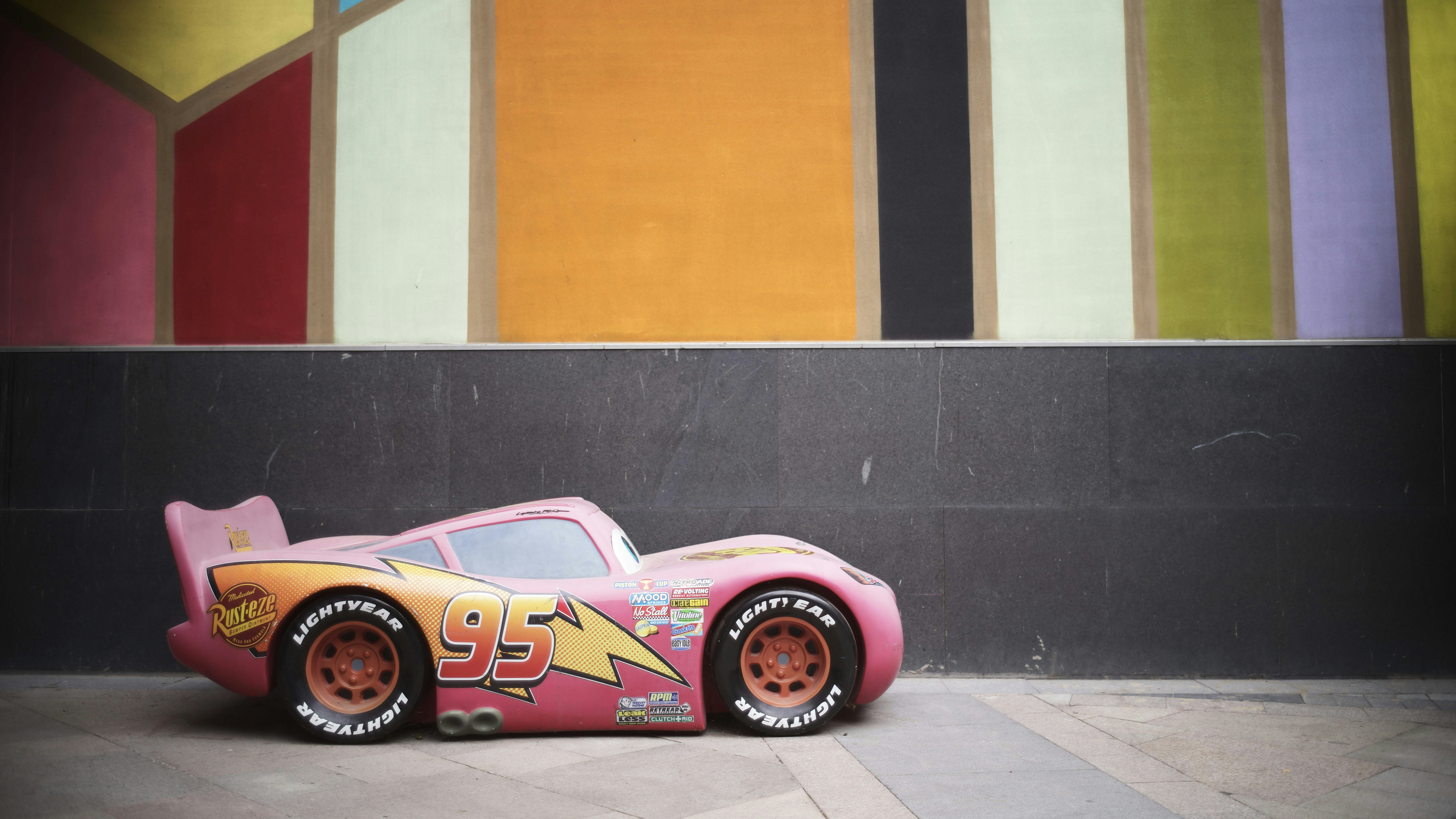 a pink toy car sitting on top of a sidewalk