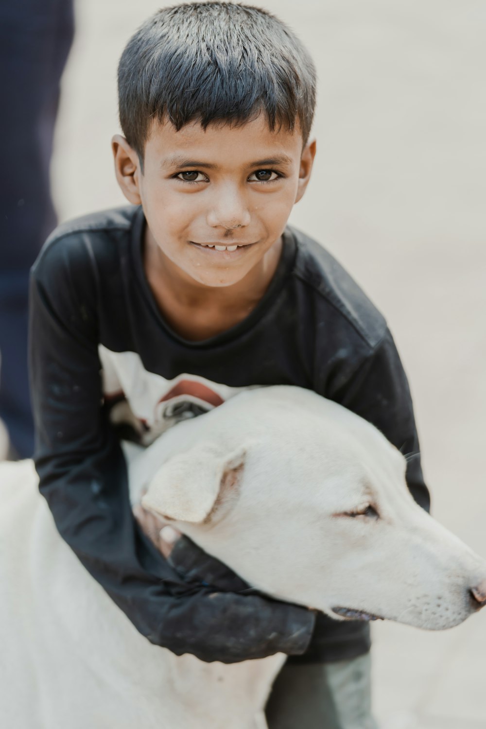 a young boy holding a white dog in his arms