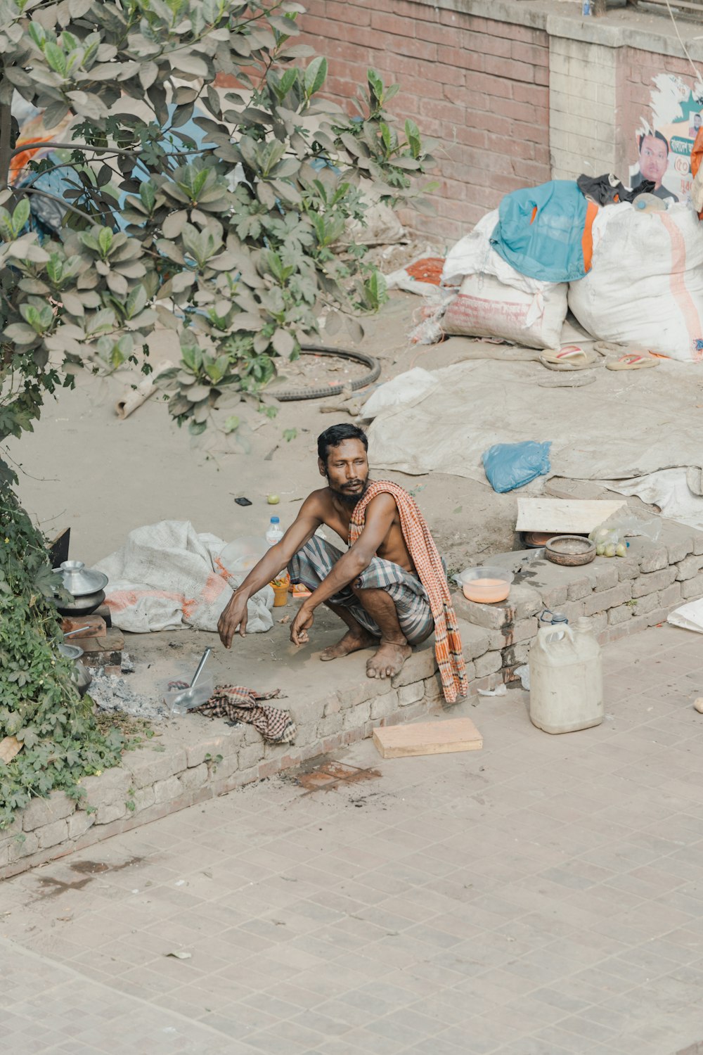 a man sitting on the ground next to a tree