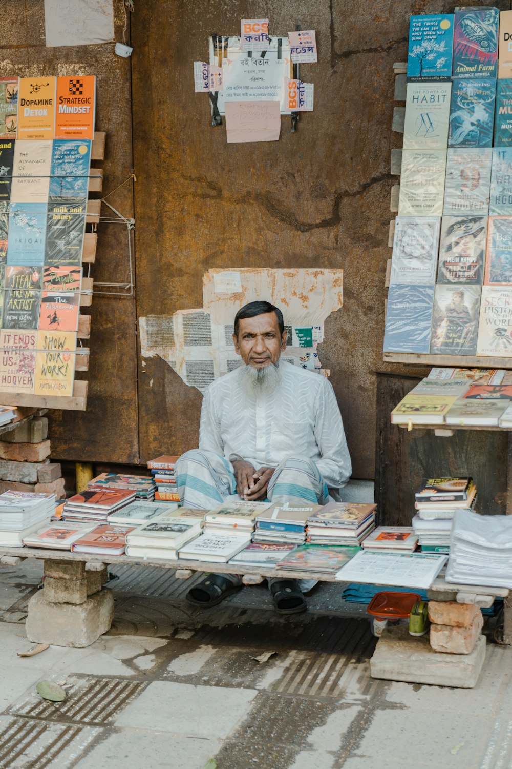 a man sitting on a bench surrounded by books