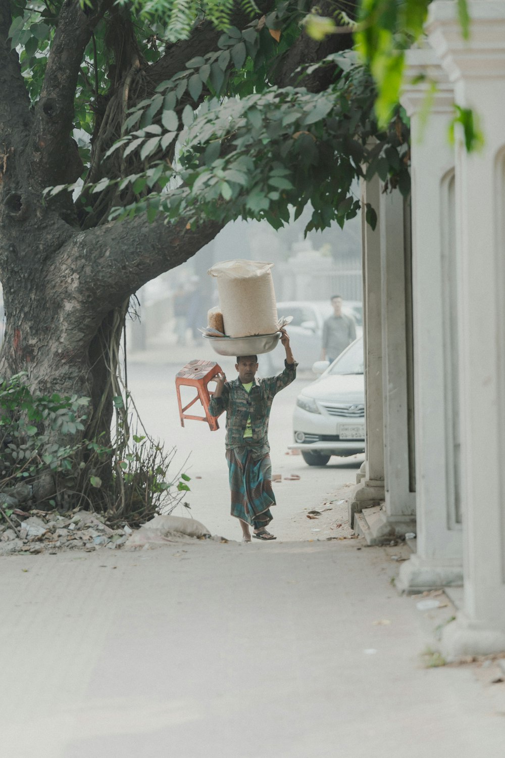 a young boy carrying a large hat on his head