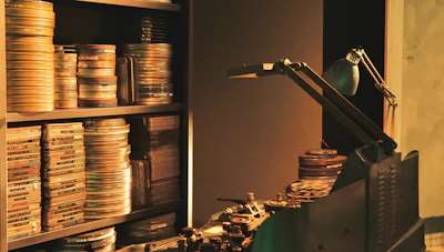 Close-up of a film reel and editing tools on a black desk.