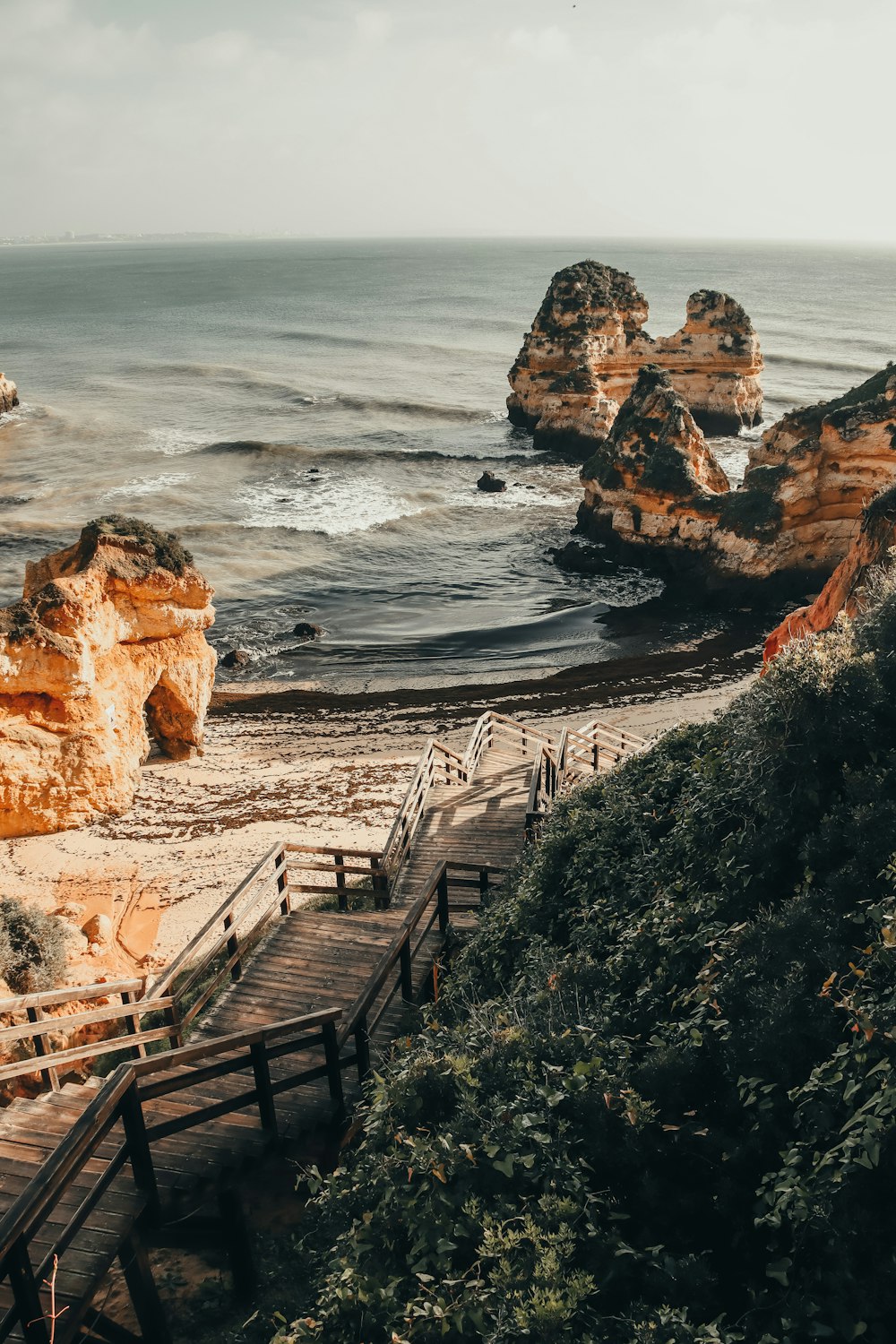 a wooden walkway leading to a beach next to the ocean