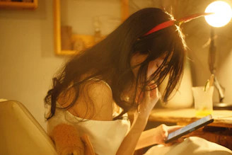 A cheerful young woman practicing language learning on her tablet in a cozy, softly lit room.