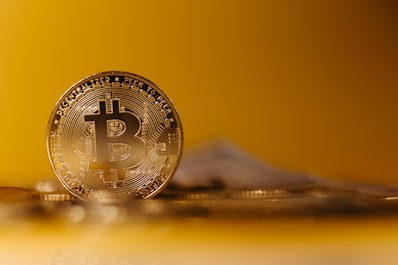 Close-up image of a Bitcoin coin leaning against a digital wallet.